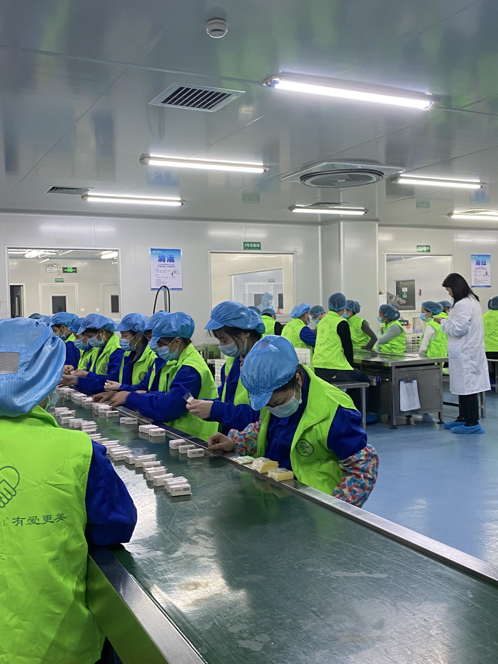 Workers packing essential oil kits on a long line in the Guangzhou packing hall